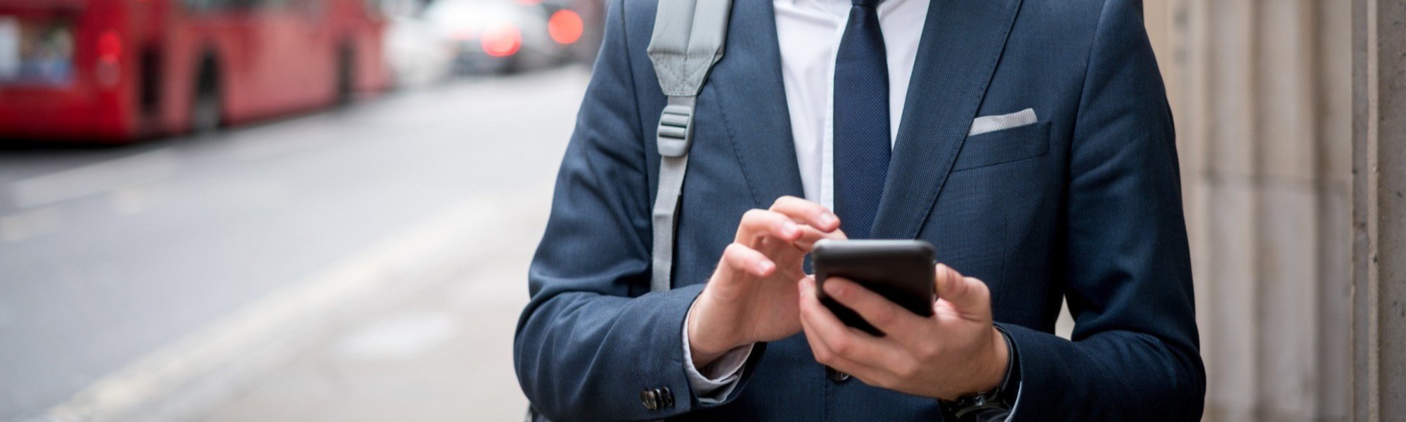 Young business man in suit texting on the street looking at phone